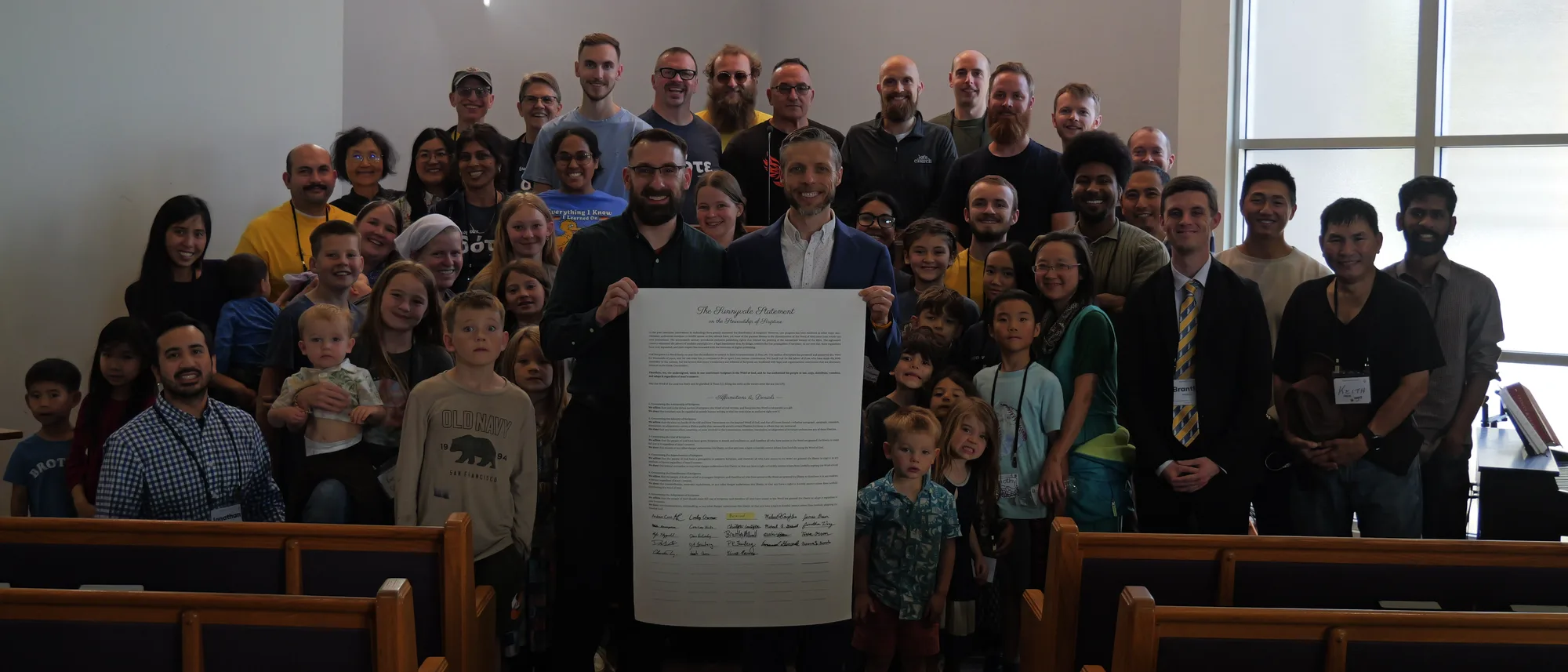 Conference attendees gathered in the sanctuary, holding a framed copy of the Sunnyvale Statement